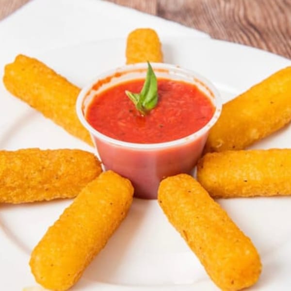 Golden-brown mozzarella sticks arranged around a cup of red marinara sauce with a basil leaf.